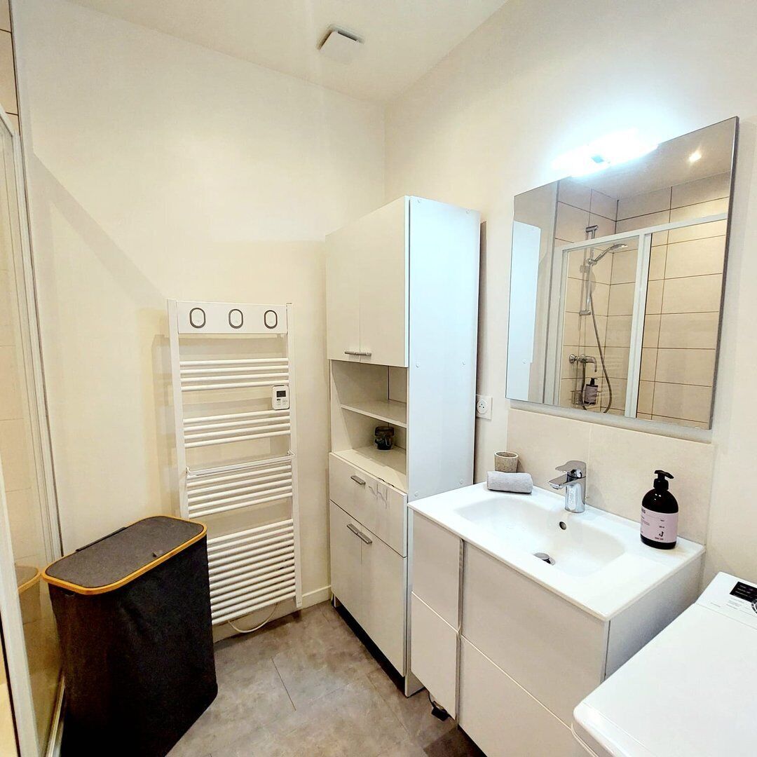Une petite salle de bain avec un lavabo blanc, un miroir et des meubles de rangement.