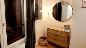 Una habitación con un ventanal grande, un espejo, un aparador y una lámpara de pie.
