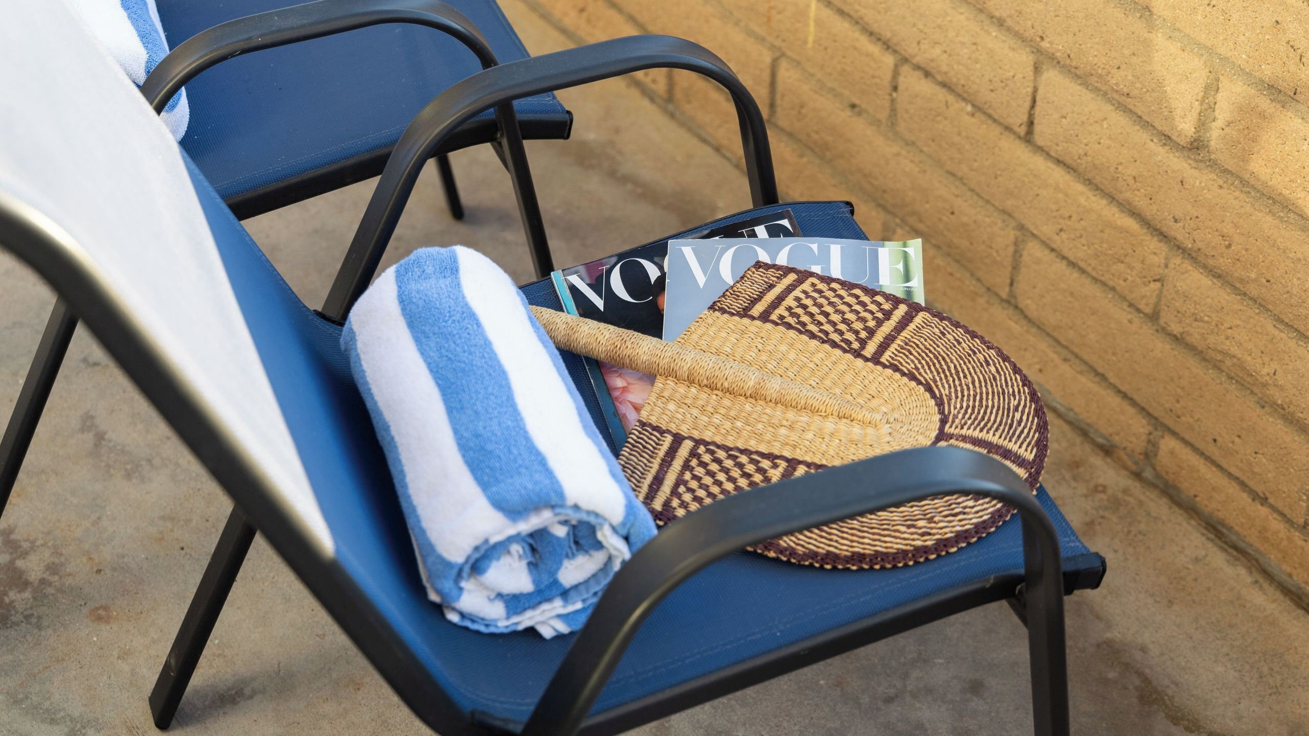 Una silla azul con una toalla enrollada y un bolso tejido.
