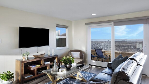 Una sala de estar con televisión, sofá, mesa de centro y un balcón con vistas.