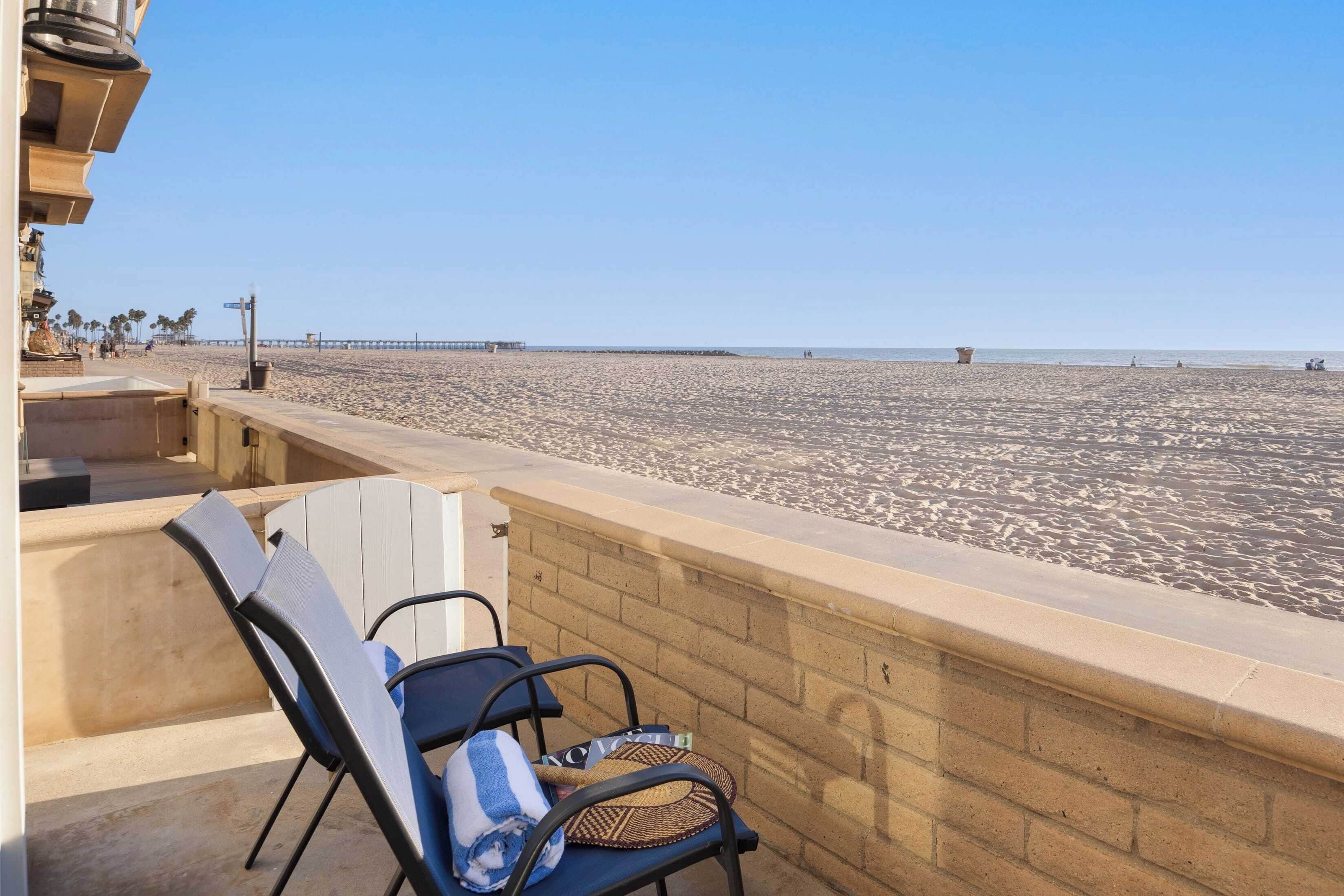 A beach view with a concrete barrier, a chair, and a towel.
