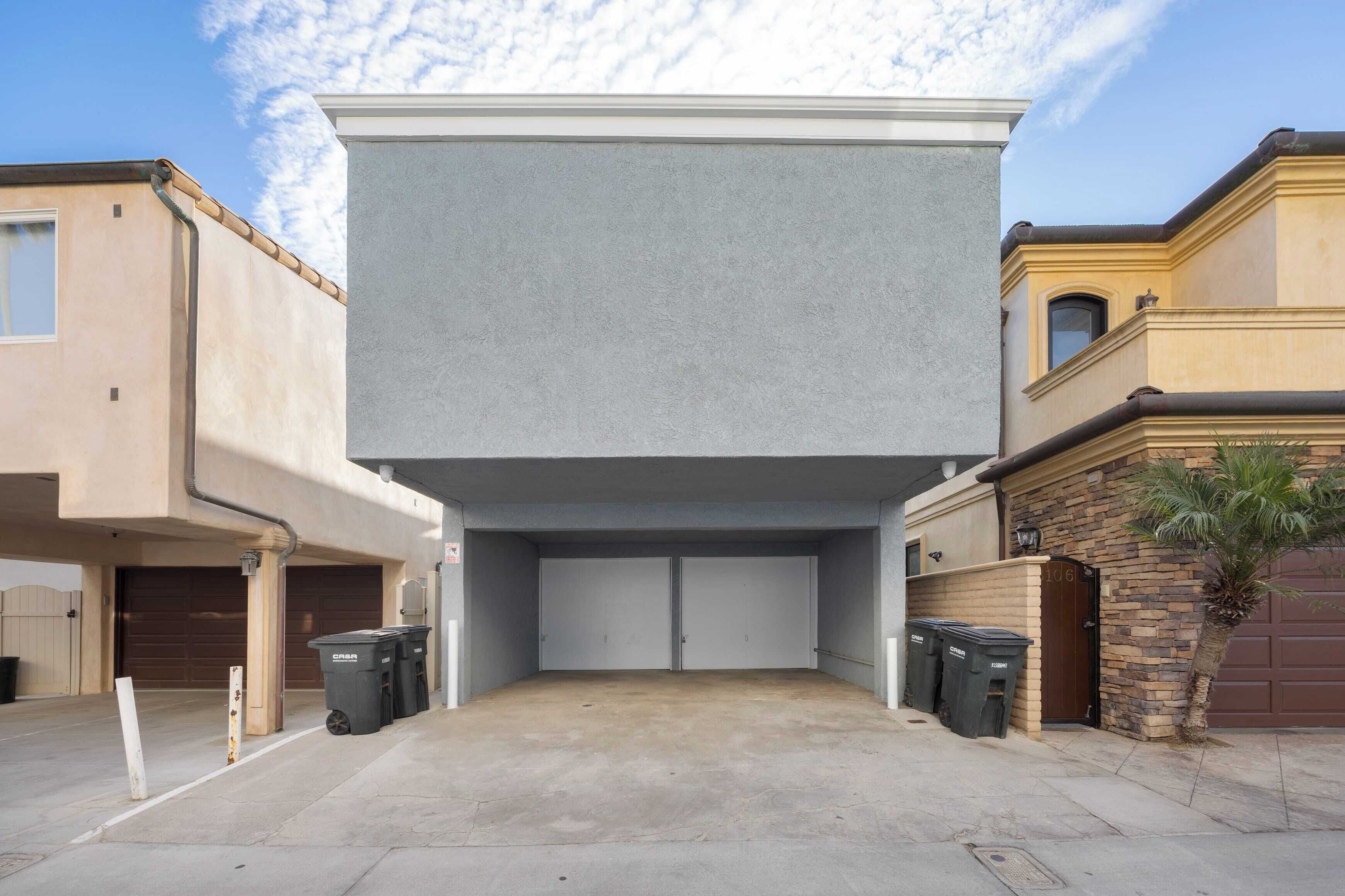 Een moderne garage met plat dak, twee garage deuren en een betonnen oprit.