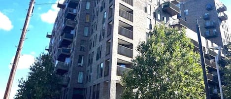 A multi-story building with a modern architectural design, featuring balconies and a brick facade.