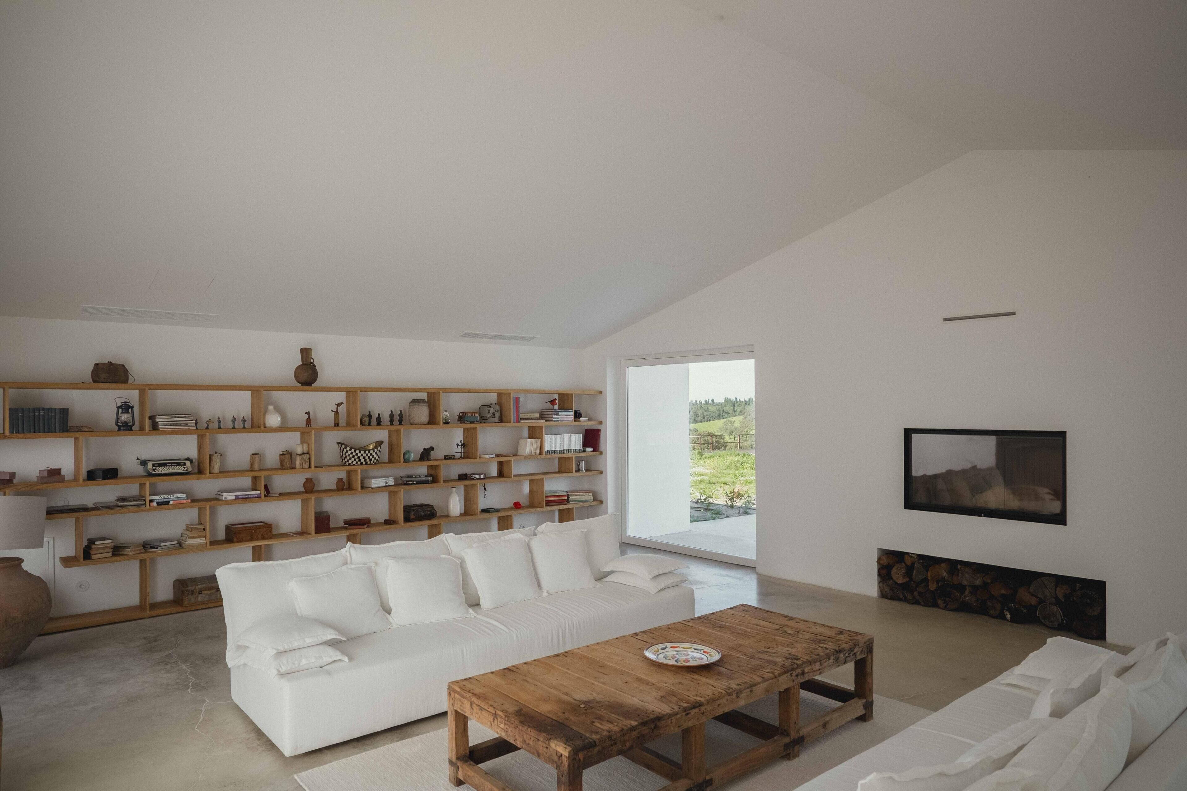 A spacious living room with a white sofa, wooden coffee table, and a bookshelf filled with books and decorative items.