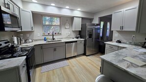 A modern kitchen with stainless steel appliances, white cabinetry, and a window providing natural light.