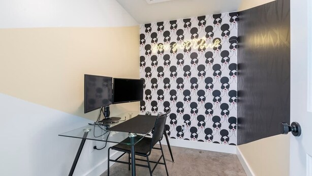 A small room with a glass table, two black chairs, a flat-screen TV, and a wall with a skull pattern wallpaper. - Gallery House: Designer Home-Hot Tub-Campfire-EV (Ithaca)