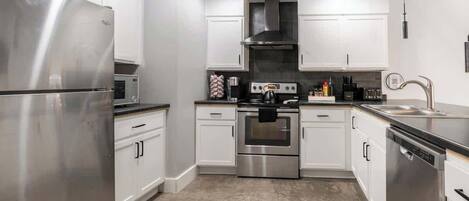 Una cocina moderna con electrodomésticos de acero inoxidable, armarios blancos y una isla central.