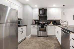 A modern kitchen with stainless steel appliances, white cabinetry, and a central island. - Gallery House: Designer Home-Hot Tub-Campfire-EV (Ithaca)