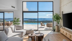 A spacious living room with large windows, a sofa, two armchairs, a coffee table, and a TV. - Luxury Villa Eloria with Pool (Rogoznica)