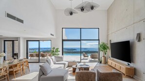 A spacious living room with a large TV, comfortable seating, a dining area, and a balcony with a scenic view. - Luxury Villa Eloria with Pool (Rogoznica)