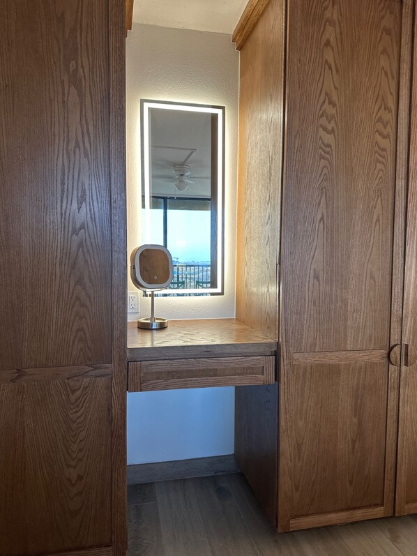 Un armario de madera con espejo y una ventana sobre un escritorio.