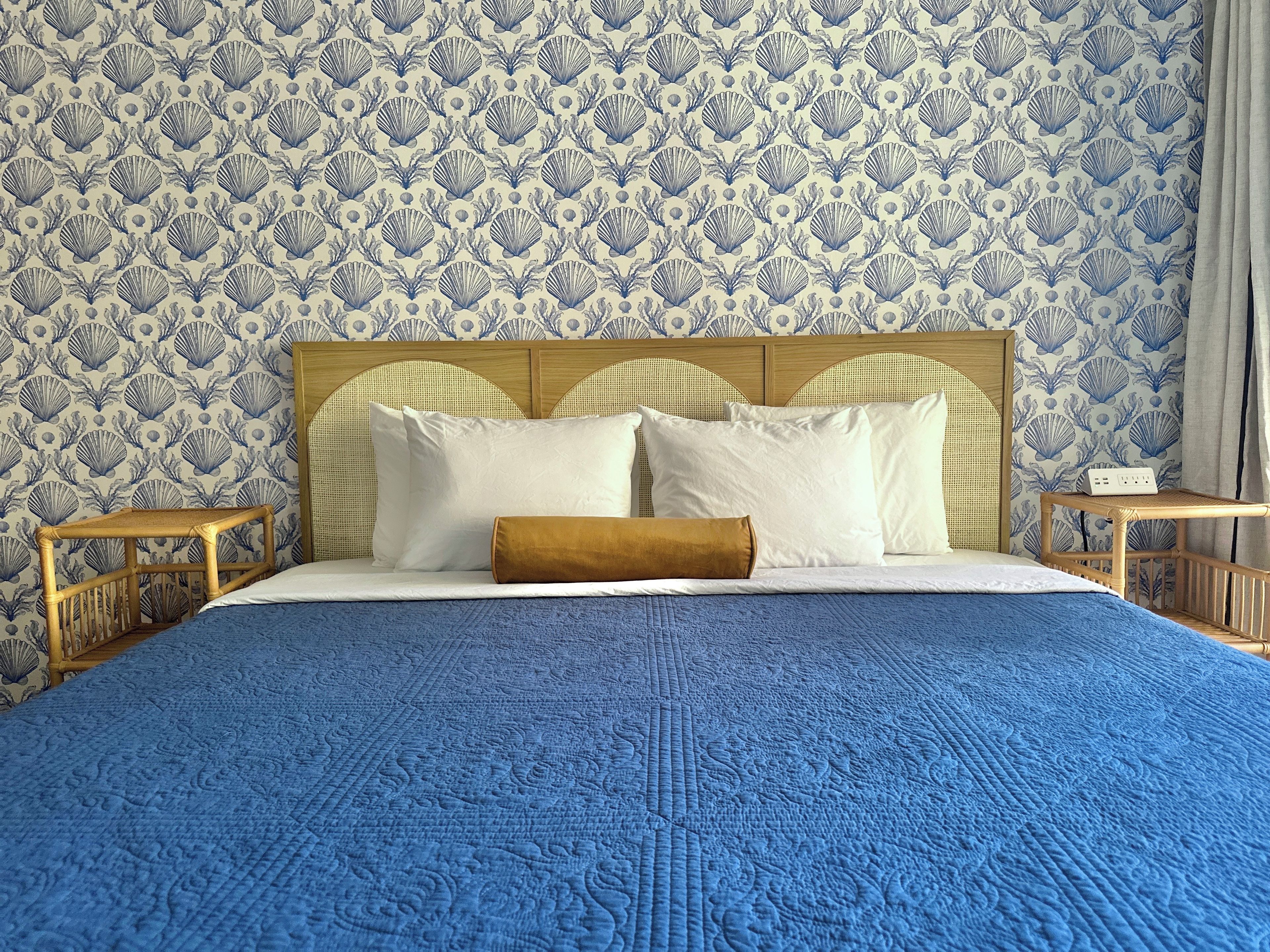 A bed with a blue quilt, white pillows, and a wooden headboard.