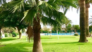 Un'area verde curata con palme, una piscina e un edificio sullo sfondo.