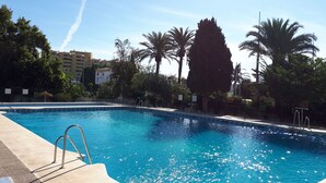 Una piscina con acqua cristallina, circondata da palme e da una recinzione.