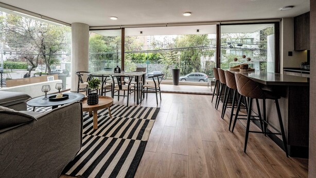 Una cocina moderna con barra, ventanas amplias y vista a la calle.