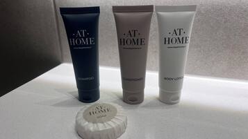 Three toiletry products labeled 'AT HOME' on a countertop.