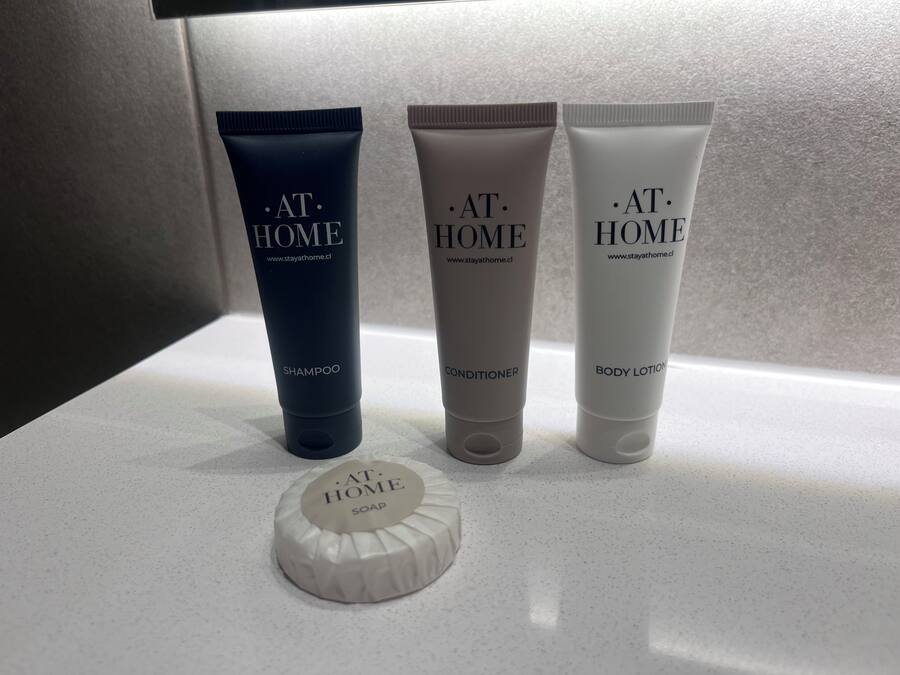 Three toiletry products labeled 'AT HOME' on a countertop.
