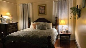 A bedroom with a large bed, two bedside tables, a nightstand, a lamp, a framed picture on the wall, and a potted plant. - 3-bedroom house in wonderful Columbus with AC, WiFi. Enjoy your stay (Columbus)