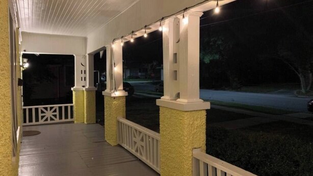 A covered porch with string lights, white railings, and columns. - 3-bedroom house in wonderful Columbus with AC, WiFi. Enjoy your stay (Columbus)