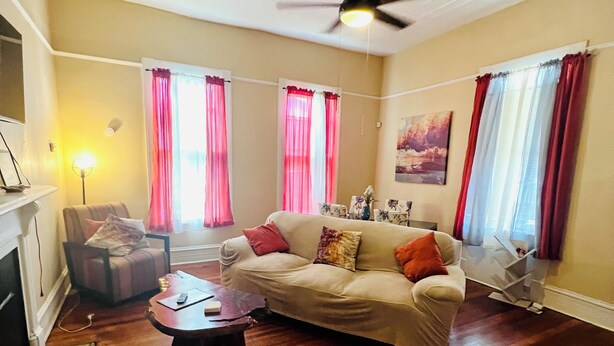A living room with a beige sofa, a coffee table, a fireplace, and a ceiling fan. - Relax and escape in this vibrant Columbus apartment (Columbus)