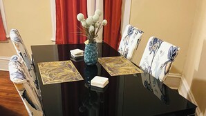 A dining table with a vase of white flowers, two placemats, and a small white object on the table. - Relax and escape in this vibrant Columbus apartment (Columbus)