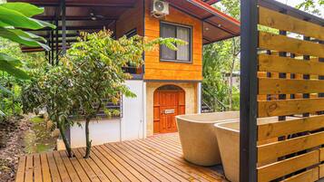 Una terraza de madera con una jardinera grande y un portón de madera.
