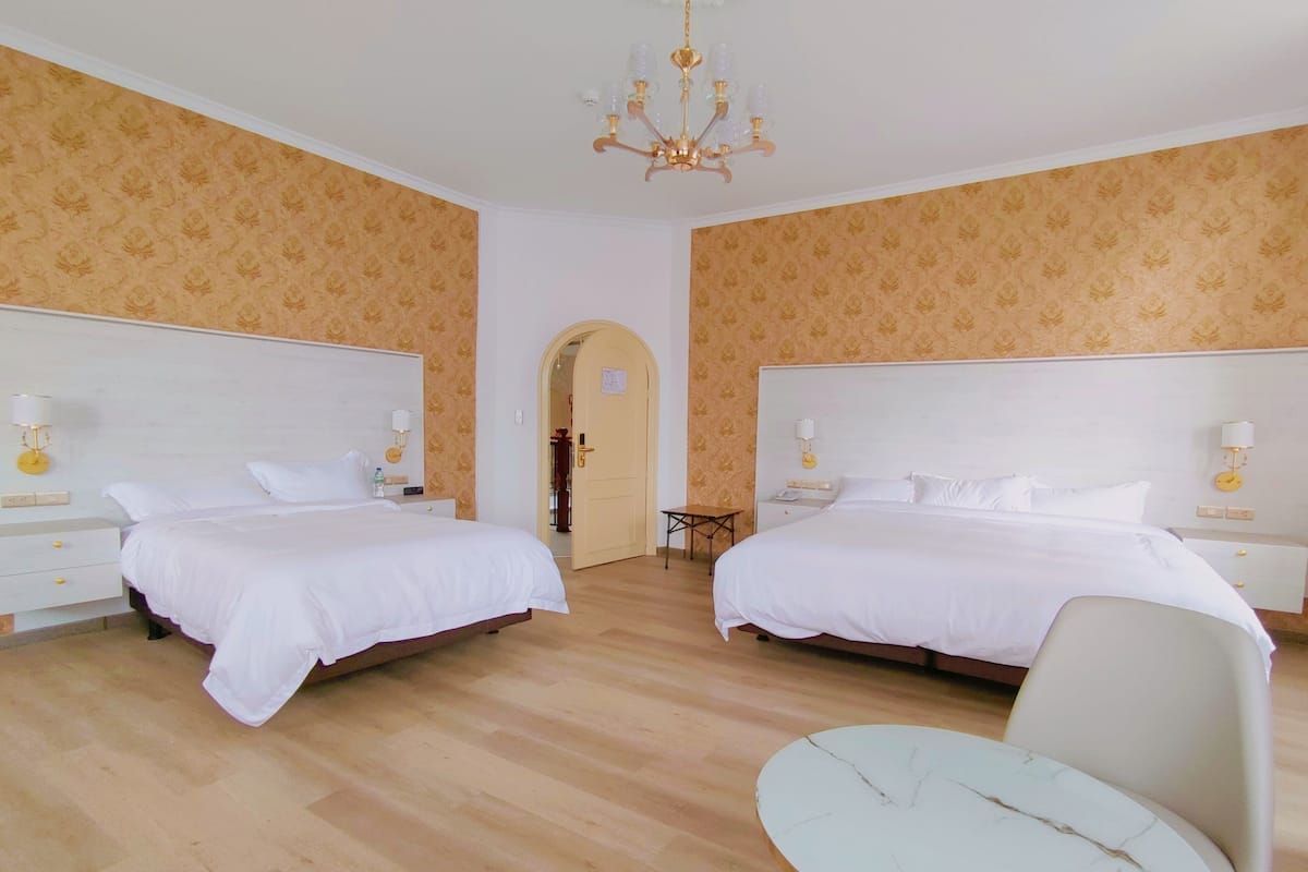 A hotel room with two beds, a chandelier, and a round table.