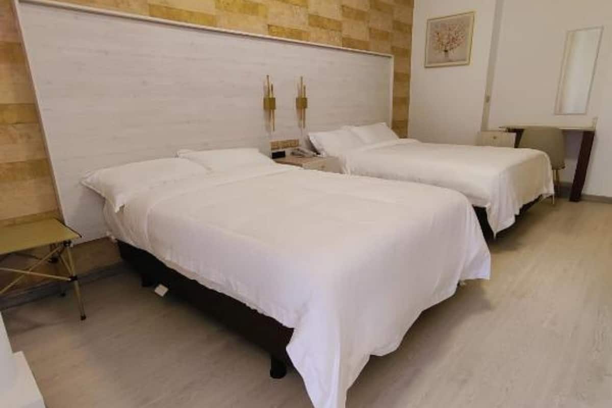 A hotel room with two beds, a wooden headboard, a small table, and a chair.