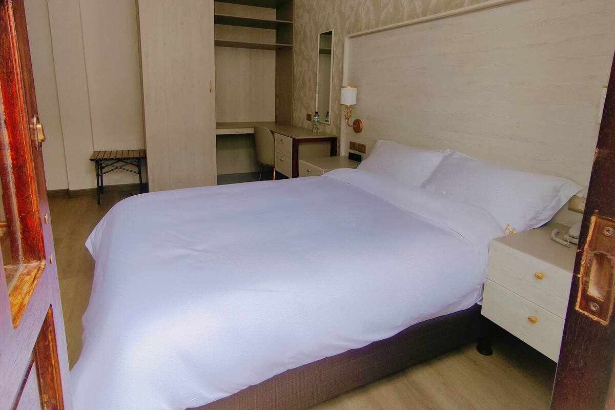 A neatly arranged bedroom with a bed, bedside table, and a wardrobe.