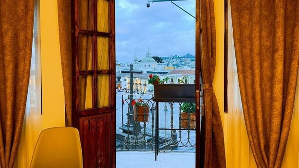 Habitación con vista a un paisaje urbano a través de una ventana con cortinas.