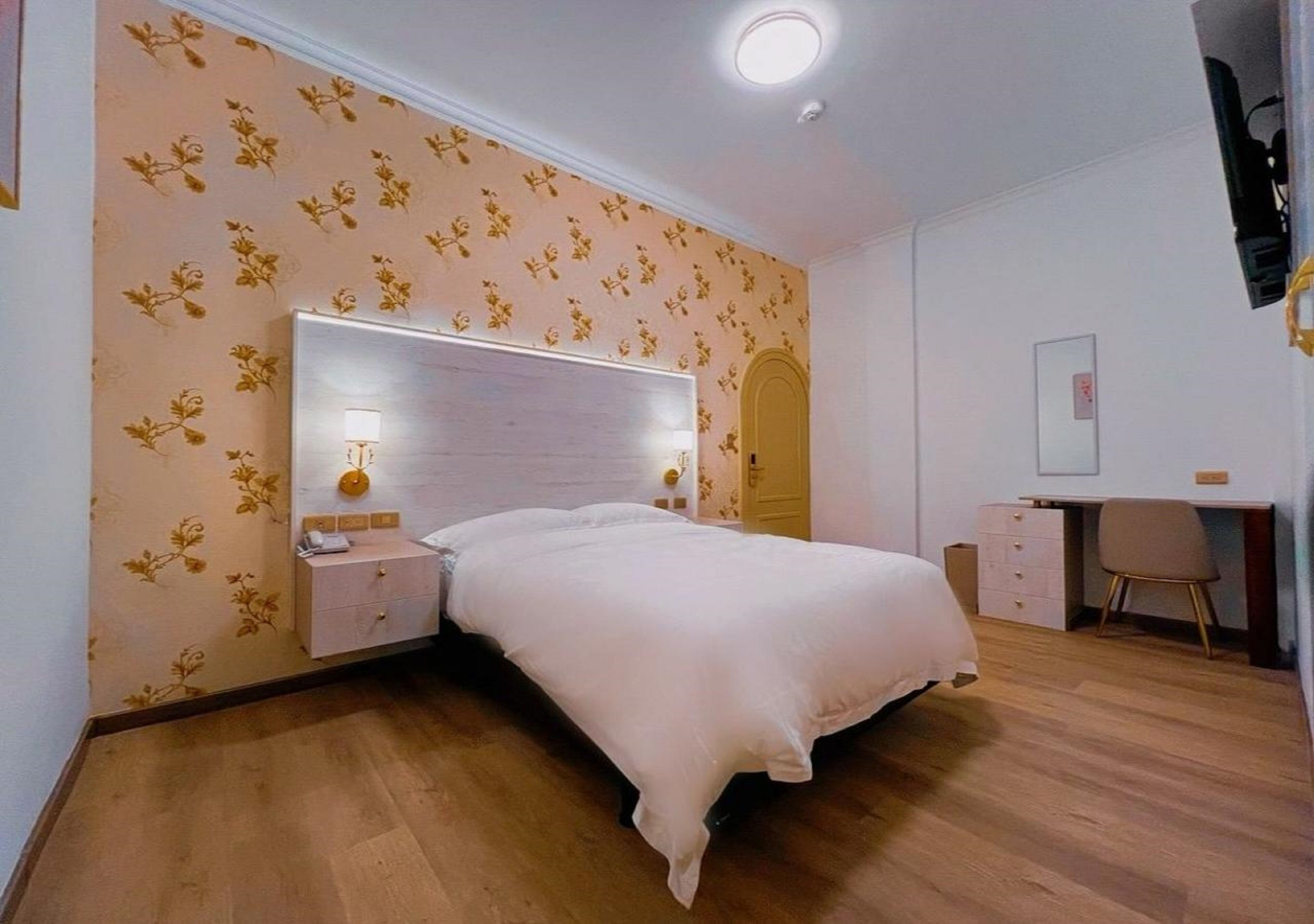 Un dormitorio con cama, mesitas de noche, un escritorio y una silla.