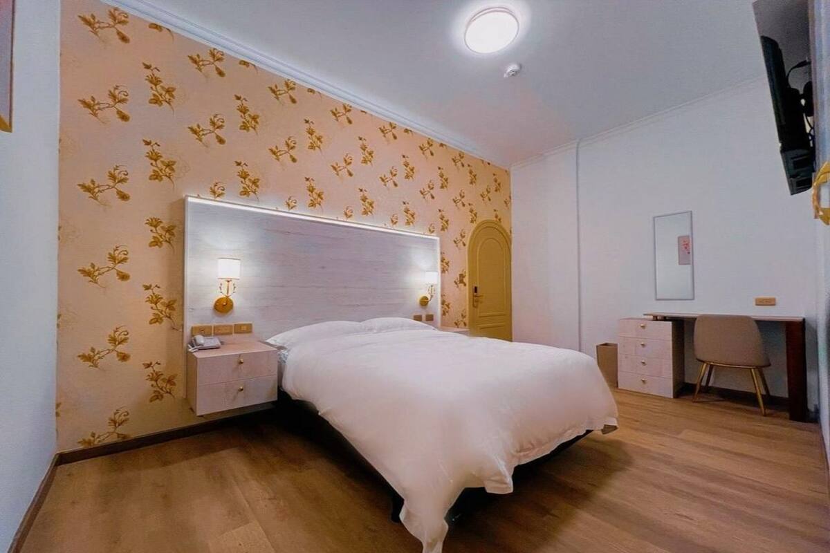 A bedroom with a bed, bedside tables, a desk, and a chair.