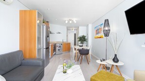 A modern living room with a grey sofa, a white coffee table with a vase, and a dining area with a table and chairs.