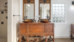 A wooden vanity with two mirrors, a window with frosted glass, and a tiled floor. - Oxnard Beach Retreat  (Oxnard)