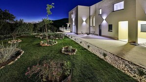 A modern building with a well-maintained garden, outdoor seating, and a clear night sky.
