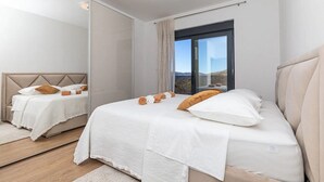 A modern bedroom with a large bed, a mirror, and a view of the outdoors.