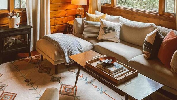 L’intérieur chaleureux d’un chalet avec un plafond en bois, un canapé, une table basse et une pancarte sur laquelle on peut lire : « Notre havre de paix ».