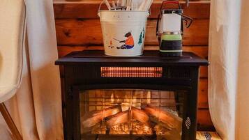 A cozy room with a wood-burning stove, a white bucket with a bear design, and a box labeled "Firestart".