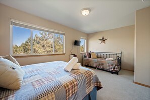 A bedroom with two beds, a star decoration on the wall, and a TV mounted on the wall. - Eagle Crest Hole in One! (Redmond)