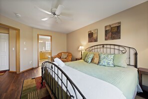 A bedroom with a bed, a chair, a nightstand, a lamp, and a ceiling fan. - Eagle Crest Hole in One! (Redmond)