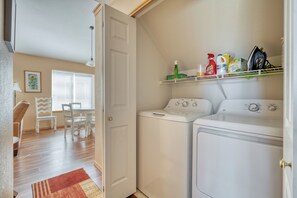 A laundry room with a washing machine, dryer, and shelves with cleaning supplies. - Eagle Crest Hole in One! (Redmond)
