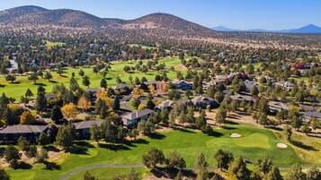 Un quartier résidentiel avec des maisons, un terrain de golf et des montagnes en arrière-plan.