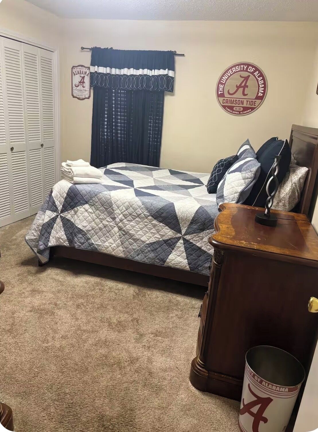 Une chambre à coucher comprenant un lit, une table de chevet, une lampe, une armoire et une décoration sur le thème de l’Alabama.