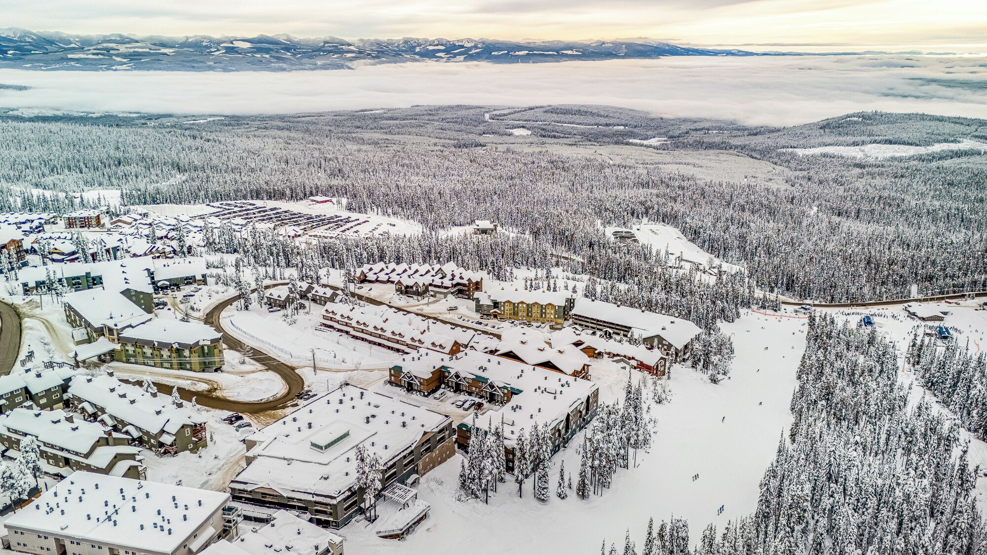 A snow-covered resort with multiple buildings, including lodges and a ski resort.