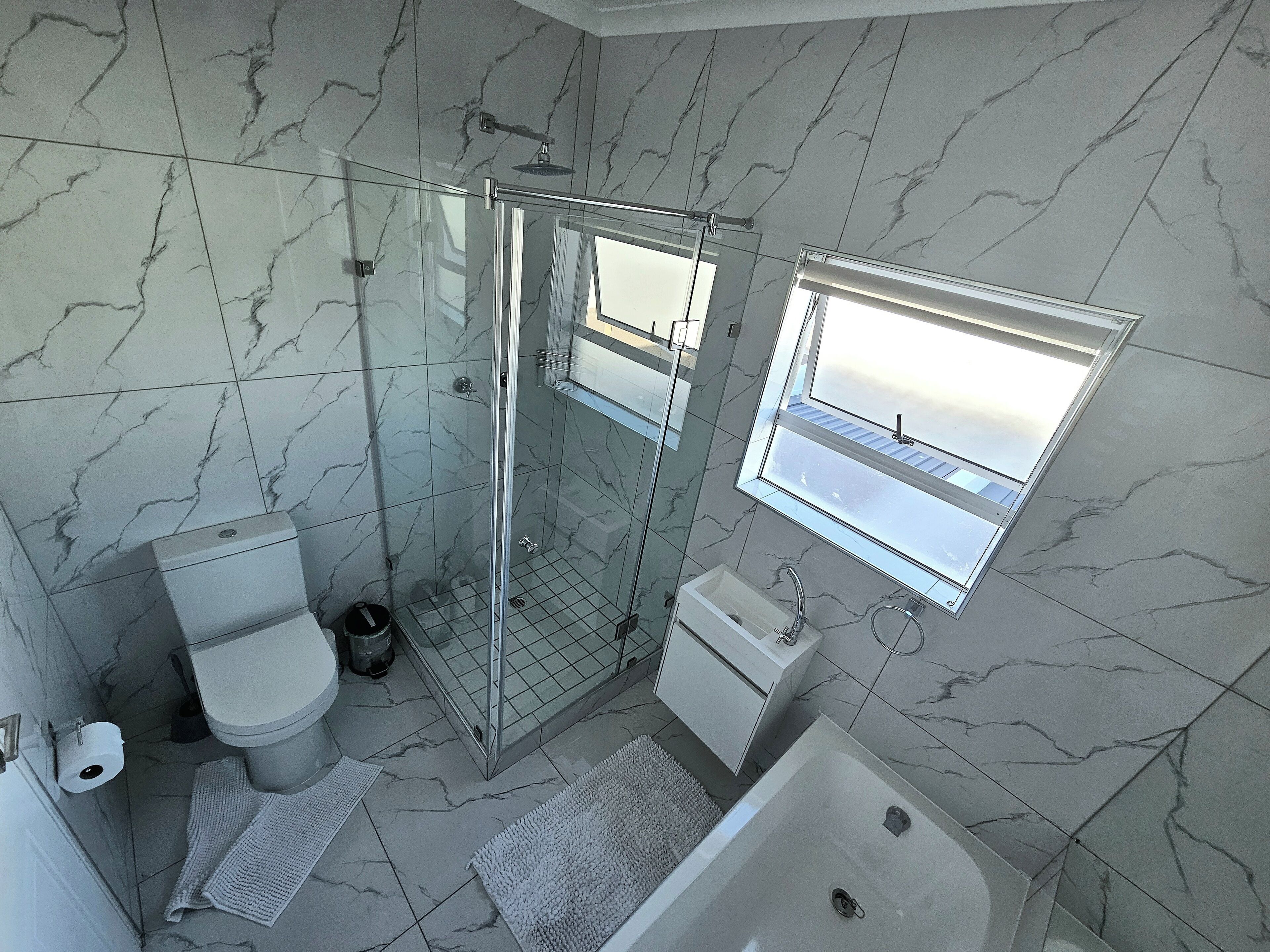 Une salle de bain moderne dotée d’une douche à parois de verre, de toilettes, d’un lavabo et d’une baignoire.