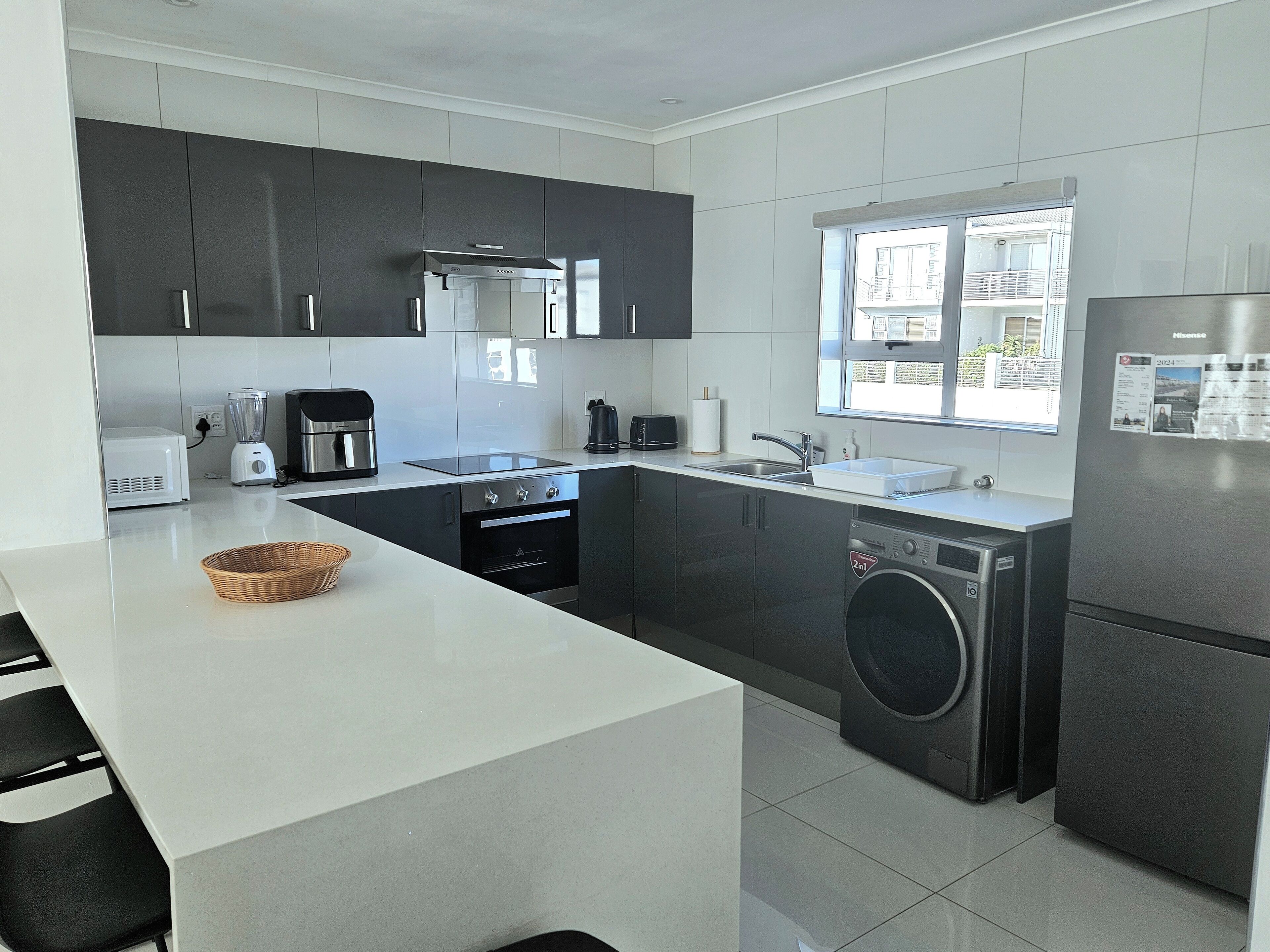 A modern kitchen with a central island, built-in appliances, and a large window.
