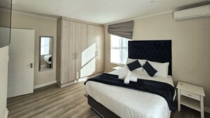 Una camera da letto moderna con un letto grande, un armadio, uno specchio e una finestra con tende.