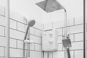 Ein modernes Badezimmer mit weißen Fliesenwänden, einer Handbrause, einer fest installierten Duschbrause und einer Bedienkonsole.