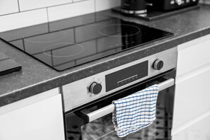 Eine Küche mit einem schwarzen Kochfeld, einem eingebauten Backofen und einer Edelstahl-Dunstabzugshaube.