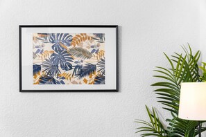 A framed tropical-themed artwork on a textured wall.